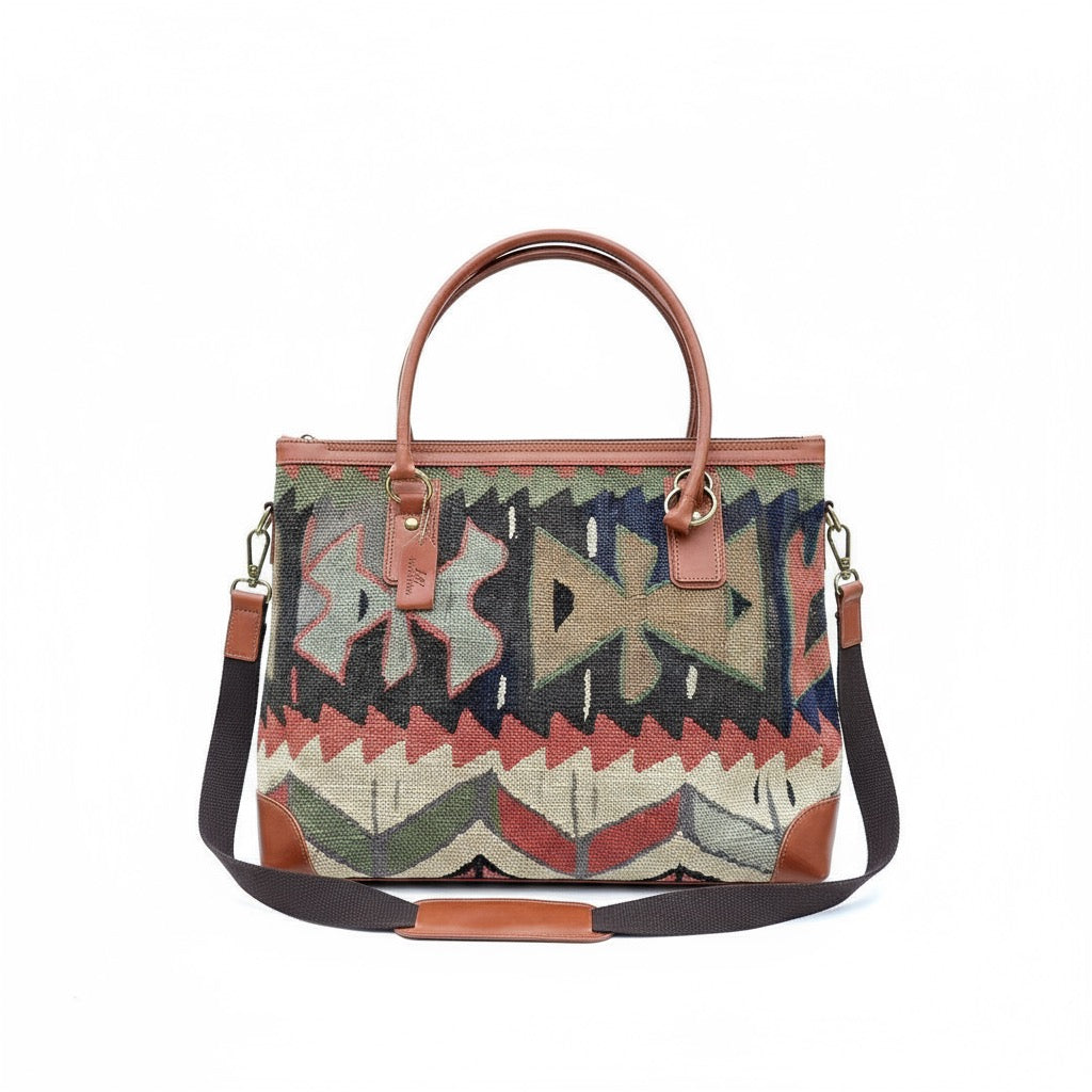 Multicolored patterned handbag with brown handles and strap on a white background